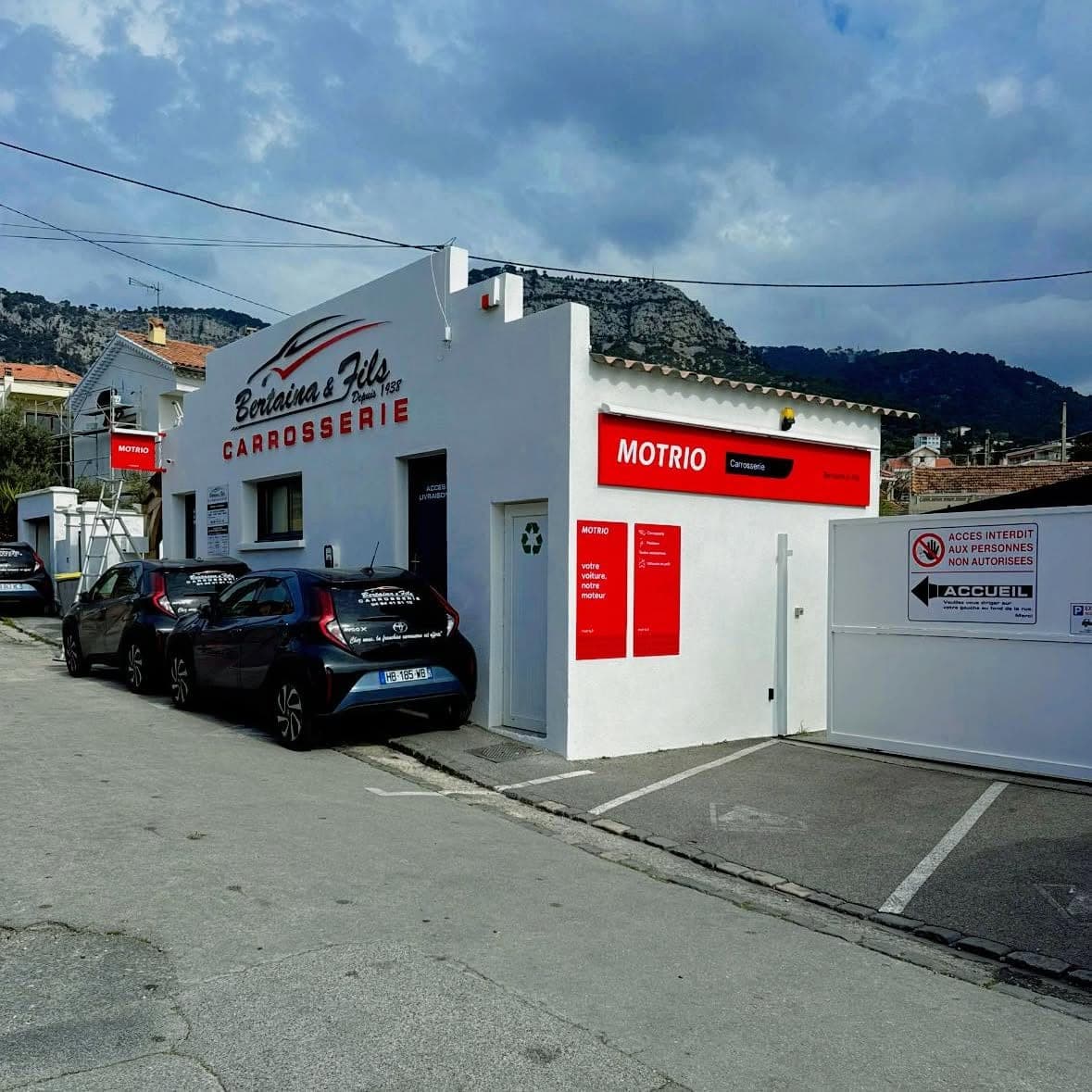 L’entrée de la carrosserie Bertaina et Fils : accès livraisons, panneau Motrio « votre voiture, notre moteur » et portail d’accueil.